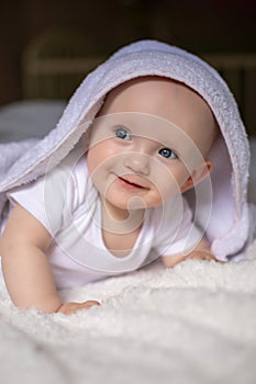 smiling baby looking at camera under a white blanket, towel