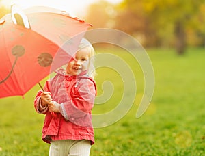 Smiling baby looking out from red umbrella