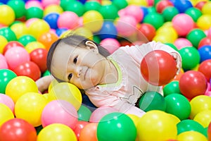 Smiling baby playing in the balls pool. Cute and happy girl. Picture for developmental in children concept. photo