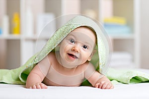 Smiling baby after shower or bath with towel on