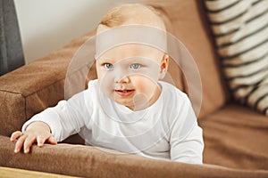 Smiling baby standing at the sofa relying on support.