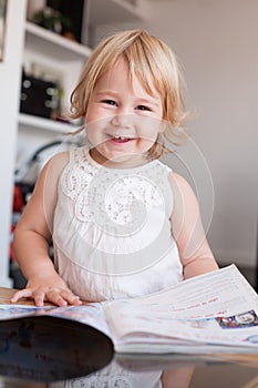 Smiling baby thumbing magazine