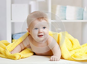 Smiling baby under soft towel. Cute child lying on bed after bathing in bedroom