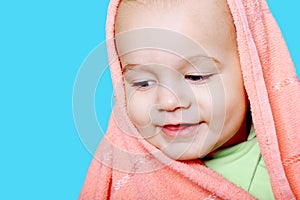 Smiling baby wrapped in a pink towel