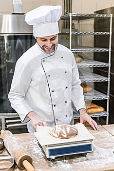 smiling baker weighing raw dough