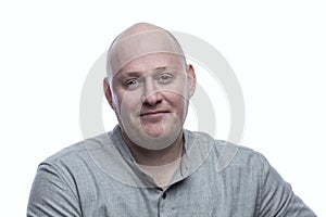 Smiling bald man in a gray shirt. Success and positivity. Isolated on a white background. Close-up