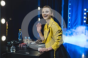 smiling ballerina in yellow leather jacket applying makeup