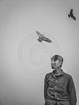 Smiling Bangladeshis man looking at something under two flying birds - freedom concept photo