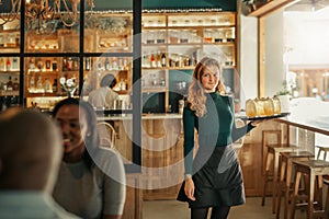 Smiling bar waitress standing with a tray of drinks