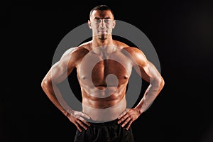 Smiling bare chested male body builder with hands on hips