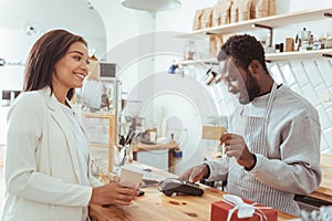 Smiling barista carrying out payment procedure