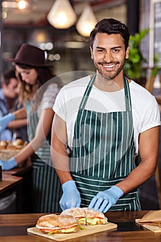 Smiling barista cutting sandwich