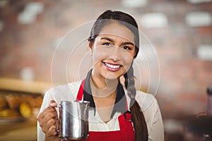 Smiling barista holding a milk jug