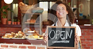 Smiling barista holding an open signboard