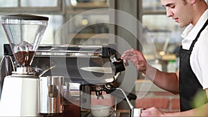 Smiling barista steaming milk at the coffee machine