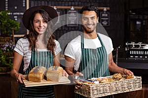 Smiling baristas holding bread and desserts