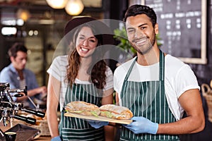 Smiling baristas holding sandwiches