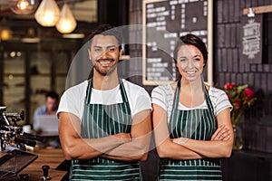 Smiling baristas standing with arms crossed