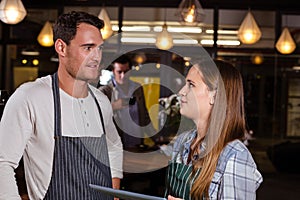 Smiling baristas talking while holding tablet