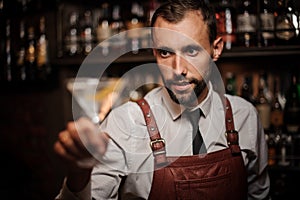 Smiling bartender holding a transparent cocktail in the martini