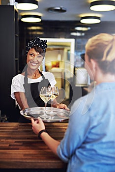 Smiling bartender serving glasses of white wine