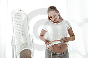 Smiling beaming woman with wide smile attaching measuring tape