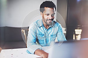 Smiling bearded African man working on laptop while spending time at coworking office.Concept of young business people