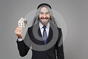 Smiling bearded arabian muslim businessman in keffiyeh kafiya ring igal agal classic black suit tie isolated on gray