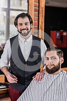 smiling bearded barber with client