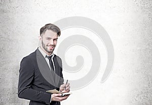 Smiling bearded businessman, concrete wall