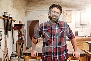 Smiling bearded craftsman in his woodwork studio