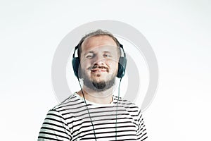 Smiling bearded happy man listens to music with big headphones. 30-35 years old. Isolated on white.