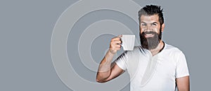 Smiling bearded hipster man holding cup of coffee or tea. Handsome mans holds cup of coffee, tea. Bearded man smiling