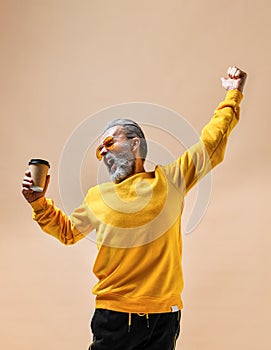 Smiling bearded hipster man holding plastic cup.