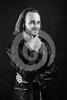 smiling bearded man biker in leather jacket with long hair, punk style