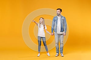 Smiling bearded man in casual clothes with child baby girl. Father little kid daughter isolated on yellow background