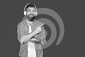 smiling bearded man listen to music pointing finger on headphones