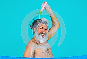 Smiling bearded man pouring shampoo on head. Male haircare. Washing hair. Taking shower. Bath time.