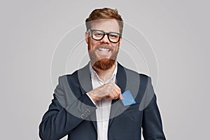 Smiling bearded man showing credit card in pocket