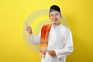 Smiling bearded Young Asian muslim man pointing the copy space to presenting something