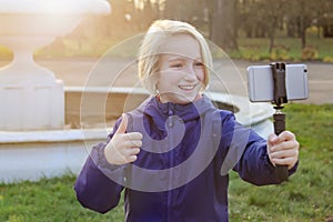 Smiling beatiful preteen girl 9-11 year old taking a selfie outdoors. Child taking a self portrait with mobile phone