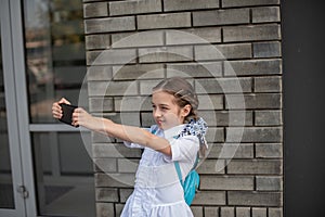 Smiling beatiful preteen girl taking a selfie outdoors. Child taking a self portrait with mobile phone. technology