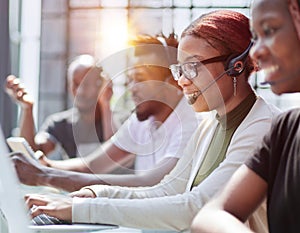 Smiling beautiful African American woman working in call center with diverse team