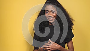 Smiling beautiful African American young woman with clean healthy skin on yellow background. Smiling dreamy beautiful