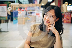 Smiling beautiful asian woman sitting in cafeteria at shopping mall