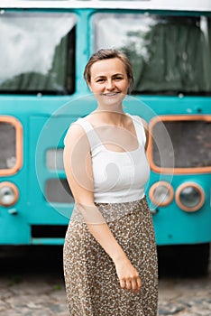 A smiling beautiful blonde is standing in the background of the old school bus