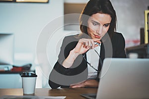 Smiling beautiful businesswoman using laptop computer at modern office.Blurred background.Horizontal.