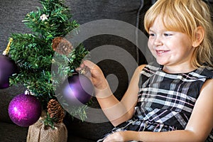 Smiling beautiful child decorating Christmas tree with balls