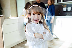 Smiling beautiful child posing and looking at camera in the kitchen at home