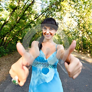 Smiling beautiful girl in blue dress showing sign OK